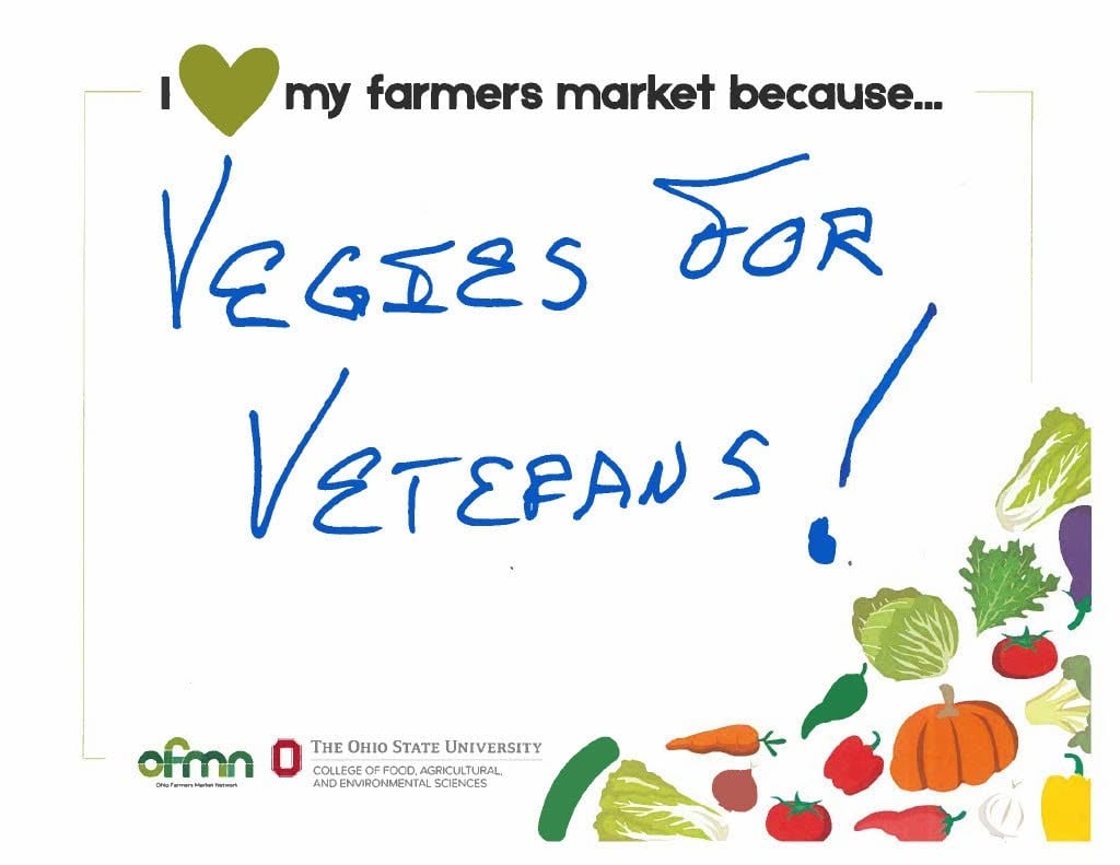 A handwritten sign says, “Veggies for veterans!” on a card with vegetable illustrations and The Ohio State University College of Food, Agricultural, and Environmental Sciences logo.