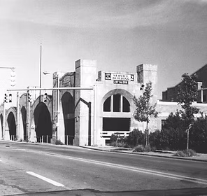 Black and white photo of a multi-arched parking garage entrance with a sign reading "Municipal Parking 2, Cars 50¢ Each.